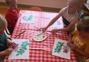 dzieci przy stoliku naklejają czerwoną plastelinę w miejsce grona jarzębiny na kartce
